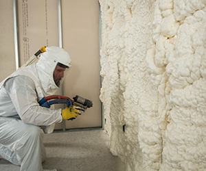 Man installing open cell spray foam in metal stud wall.